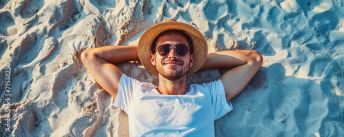 un homme allongé sur le sable, les bras derrière la tête, en train de se reposer pendant les vacances d'été, vu de dessus photo