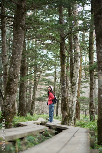 Scenic trek, Asian woman in a pink fleece explores Japan's jungle path. Alone in the amazing wilderness, enjoying the freshness and abstract beauty of nature.