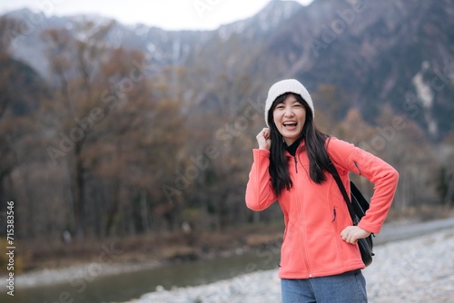 Solitary adventure, Asian woman in a pink fleece climbing alone. Elegant portrait by the lake capturing the achievement, excitement, and scenic beauty of Japan.