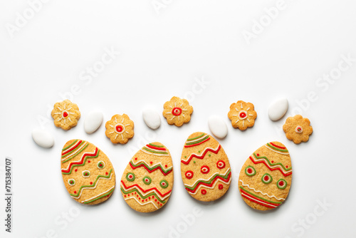Easter background. Egg shaped cookies with colorful decoration, candies, space for your text. Creative greeting card. White background.