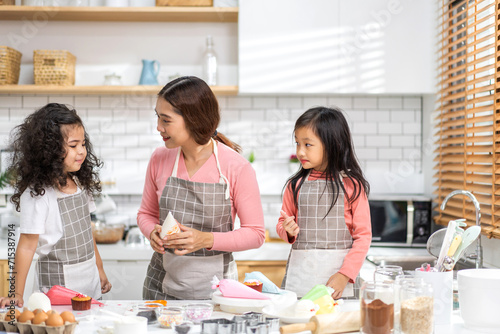 Portrait of enjoy happy love asian family mother and little toddler asian girl daughter child having fun cooking together with dough for homemade bake cookie and cake ingredient on table in kitchen.