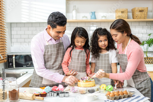 Portrait of enjoy happy love asian family father and mother with little asian girl daughter child play and having fun cooking food together with baking cookie and cake ingredient in kitchen.