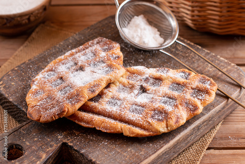 Trendy delicious croffles with Powdered Sugar on a board. Croissant as waffle.