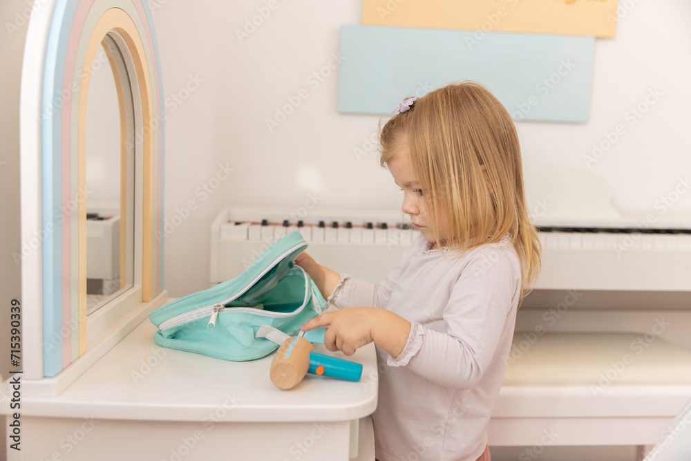 Little girl playing alone in the kindergarten with wooden toys Little girl playing alone in the kindergarten with wooden toys