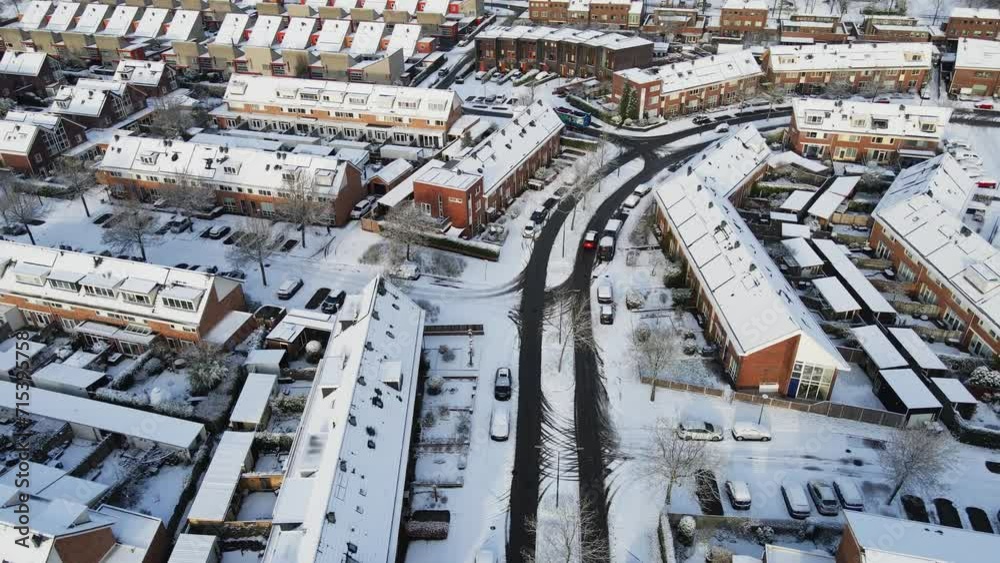 Drone following red car driving through a beautiful suburban neighborhood covered in snow Drone following red car driving through a beautiful suburban neighborhood covered in snow