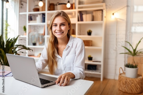 Young smiling blond girl using laptop at home