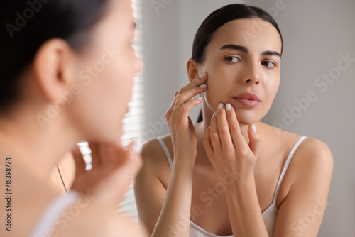 Woman with dry skin looking at mirror in bathroom