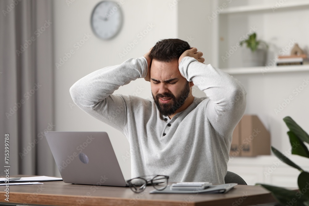 Man suffering from headache at workplace in office Man suffering from headache at workplace in office