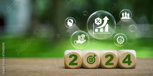Implementation of the New Year goal plan 2024. Wooden cube with year 2024 and goal icons on green background. Business plan and development to achieve goals Target achievement.