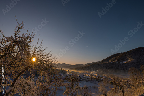 Beautiful village of Ljubno ob Savinji, home of female ski jump competition. Winter panorama from above the village in early morning. Sun rising over picturesque winterscape photo