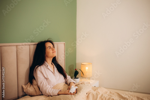 Sick woman sneezing in paper tissue on sofa photo