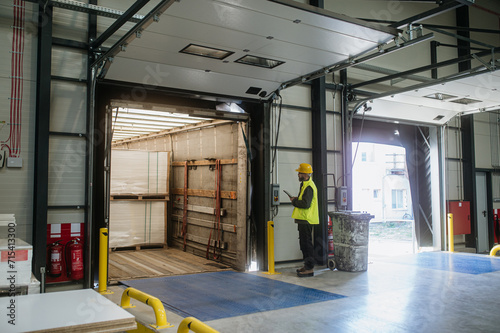 Foto Warehouse receiver overseeing the storing of delivered items, holding tablet, looking at cargo details
