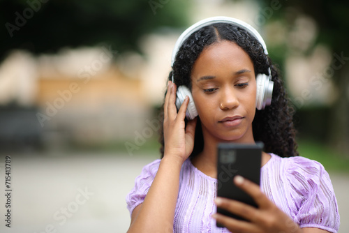 Serious black woman listening audio in the street