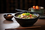 ramen in black bowl with wooden spoon, stone table