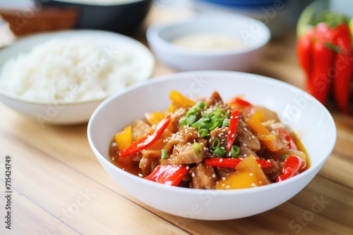 sweet and sour pork in white bowl with rice on side