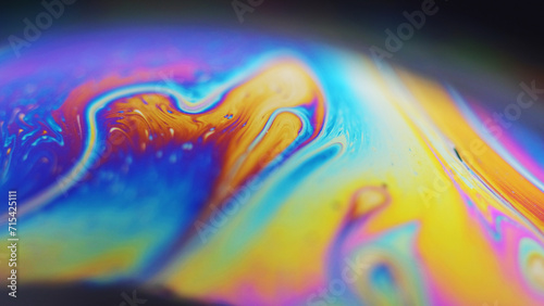 Dye mix. Oil fluid. Gasoline leak. Defocused rainbow color glowing round bubble liquid paint blend wave motion on dark green abstract art background.