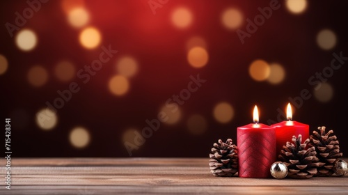  a couple of red candles sitting on top of a wooden table next to a pine cone and a christmas ornament.