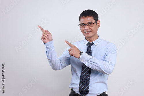Young Asian business man wear classic formal shirt tie and glasses point index finger aside on empty space isolated on white background 