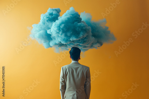 Image of a man deep in thought  with a cloud in front of him against a yellow  melancholic background. Depicting the concept of feeling sad and contemplative.