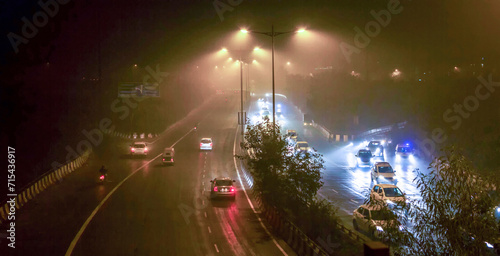 Driving at night on a busy road in New Delhi covered with dence