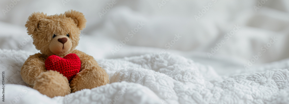 A teddy bear with a red heart on a white textured blanket, symbolizing love and affection, suitable for Valentine's Day concepts