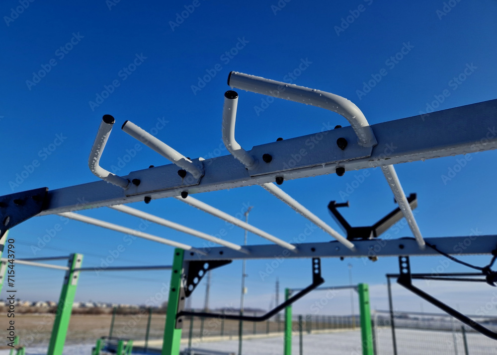 fitness sports fields with stainless steel tools resemble torture tools with chains and handles. soft rubber surface sports ground outdoor gym. man holds a pulley and strengthens muscles