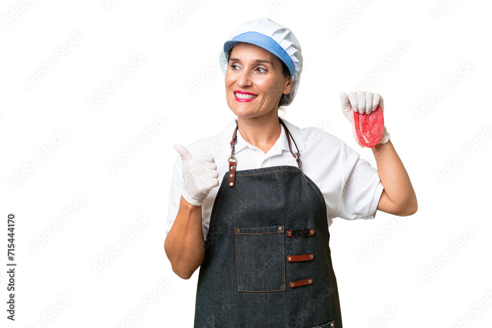 Butcher woman wearing an apron and serving fresh cut meat over isolated background pointing to the side to present a product