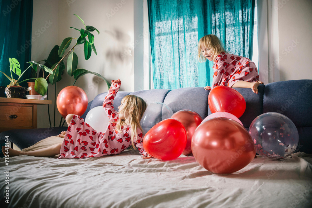 © Westend61 - Cheerful sisters playing with balloons on sofa at home © Westend61 - Cheerful sisters playing with balloons on sofa at home