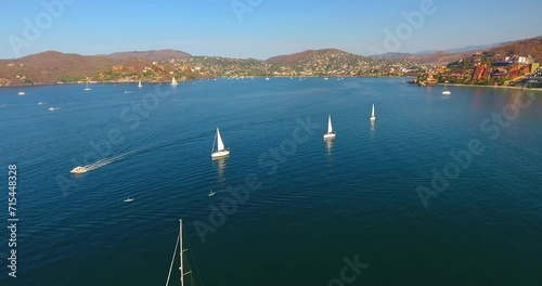 Flying down over sailboats racing around a calm water bay off the coast of Zihuatanejo, Mexico photo