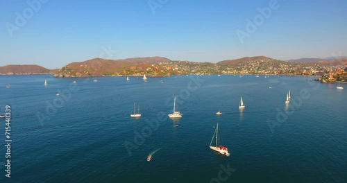 Panning over a bay filled with a regatta of sailing vessels and yachts offshore from Zihuatanejo, Mexico photo