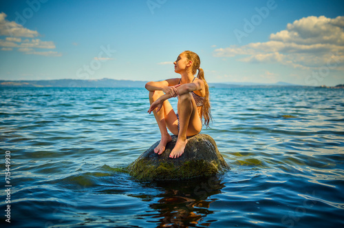 Girl sitting on rock in Lake Bolsena, Italy photo