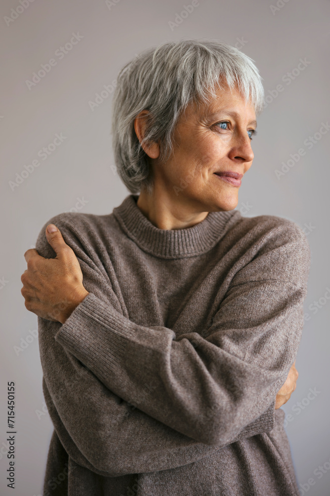 Mature woman wearing sweater against gray background Mature woman wearing sweater against gray background