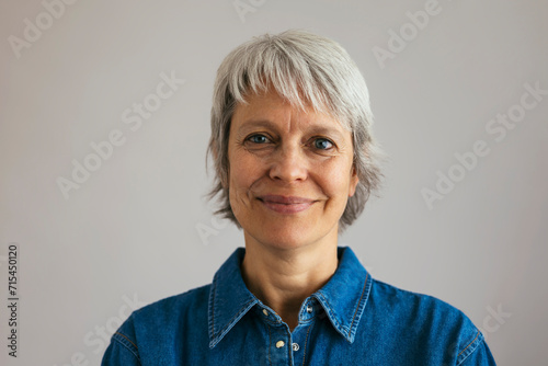 Smiling mature woman against gray background photo