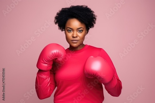 Attractive African American woman in red boxing gloves in pink top. Plus size female fighting breast cancer
