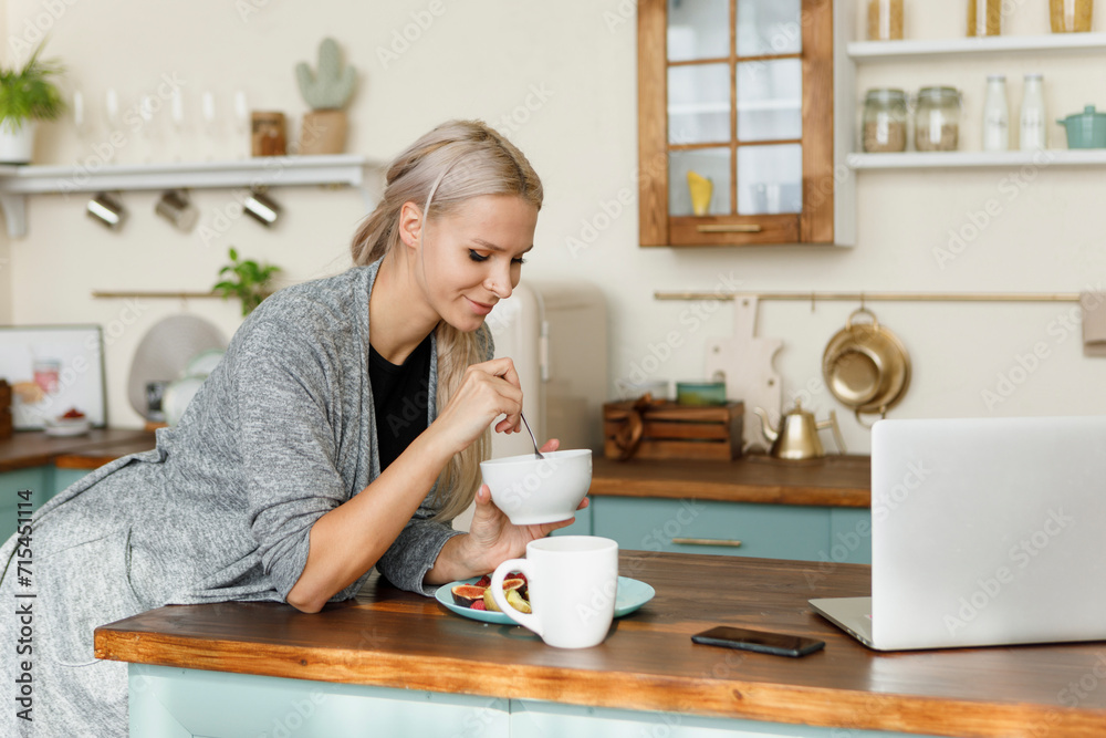 Happy woman having breakfast on kitchen island at home Happy woman having breakfast on kitchen island at home