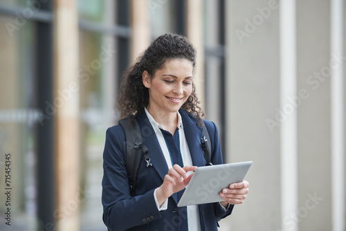Smiling curly haired businesswoman using tablet PC photo