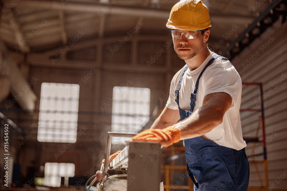 Handsome man builder using woodworking machine in workshop Handsome man builder using woodworking machine in workshop