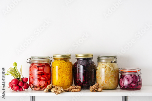 Homemade pickled vegetables in jars on shelf at home photo