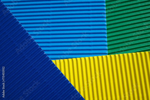 Horizontally and diagonally ribbed cardboard with the colors green, blue and yellow. Meant as background