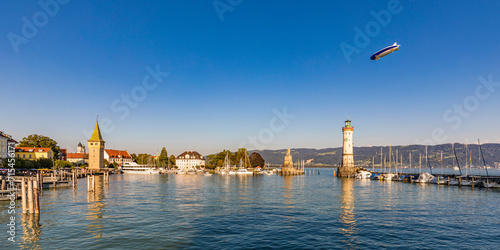 Germany, Bavaria, Lindau, Marina of town on shore of lake Bodensee with blimp flying in background