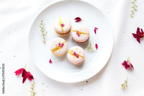 raspberry macarons with edible gold leaf accents on white plate