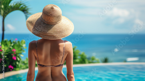Back view woman in straw hat looking on the sea. 
