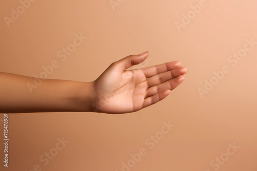 woman’s hand isolated on light brown or tan background. Empty open female hand on cream background with copy space. Close up of elegant palm faced upwards with space for your product.