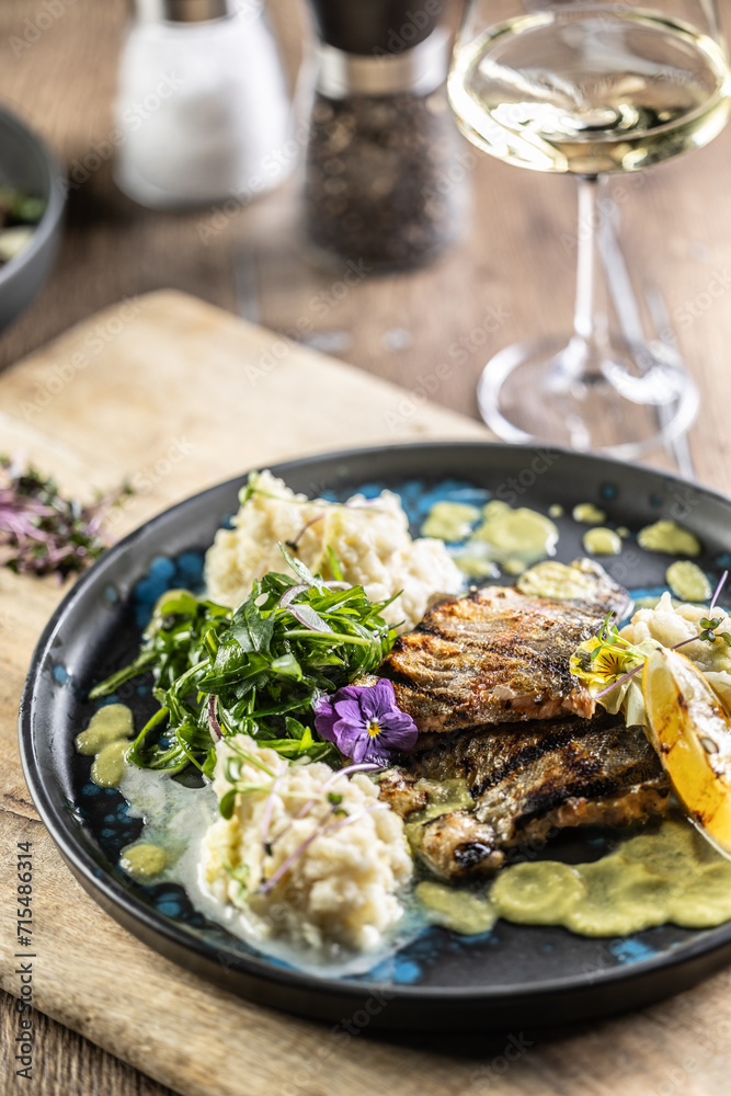 Grilled trout fillet with mashed potatoes and lemon sauce on a restaurant plate Grilled trout fillet with mashed potatoes and lemon sauce on a restaurant plate