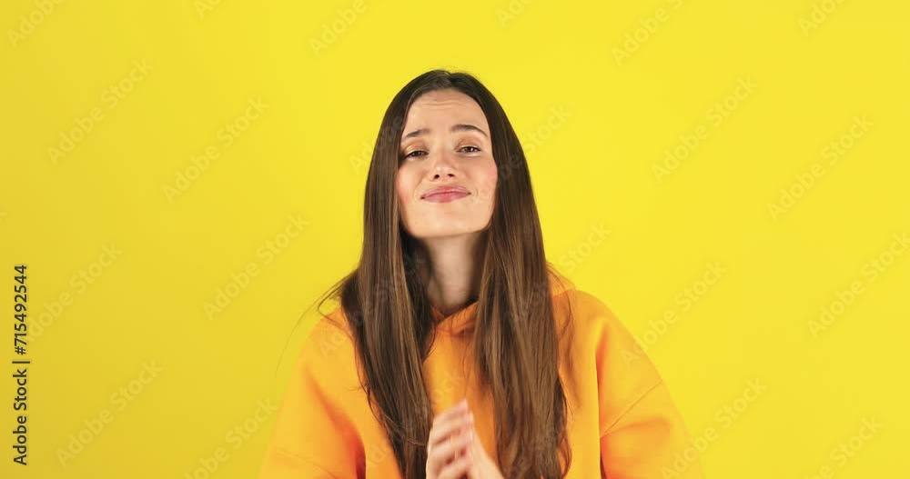 Sad attractive brunette caucasian stylish girl brunette hair in casual yellow hoody, showing, pointing two thumbs at herself, please choose me, hand in pray gesture isolated on yellow background. Sad attractive brunette caucasian stylish girl brunette hair in casual yellow hoody, showing, pointing two thumbs at herself, please choose me, hand in pray gesture isolated on yellow background.