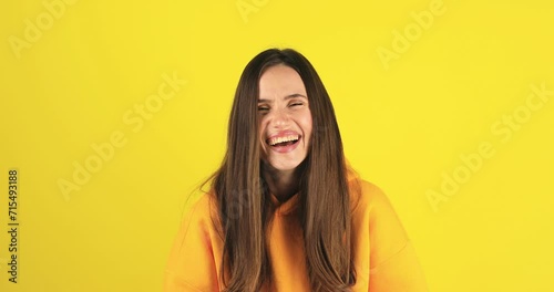 Young excited cheerful funny brunette woman look camera laugh smiling watch comedy movie, listening joke, pointing index finger on you isolated on yellow background studio portrait. photo