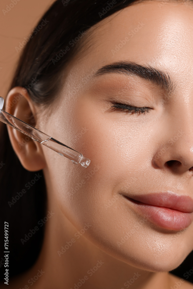 Beautiful young woman applying serum onto her face, closeup Beautiful young woman applying serum onto her face, closeup