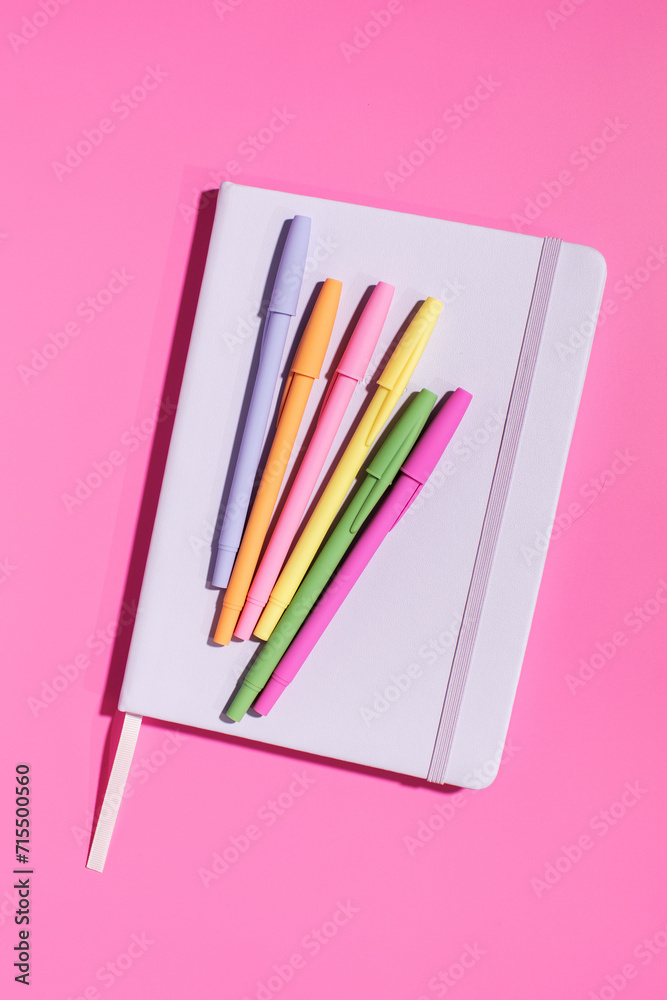 Bright notepad and pens on a pink background. Office supplies. Back to school.