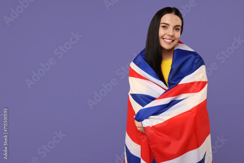 Happy young woman with flag of United Kingdom on violet background, space for text