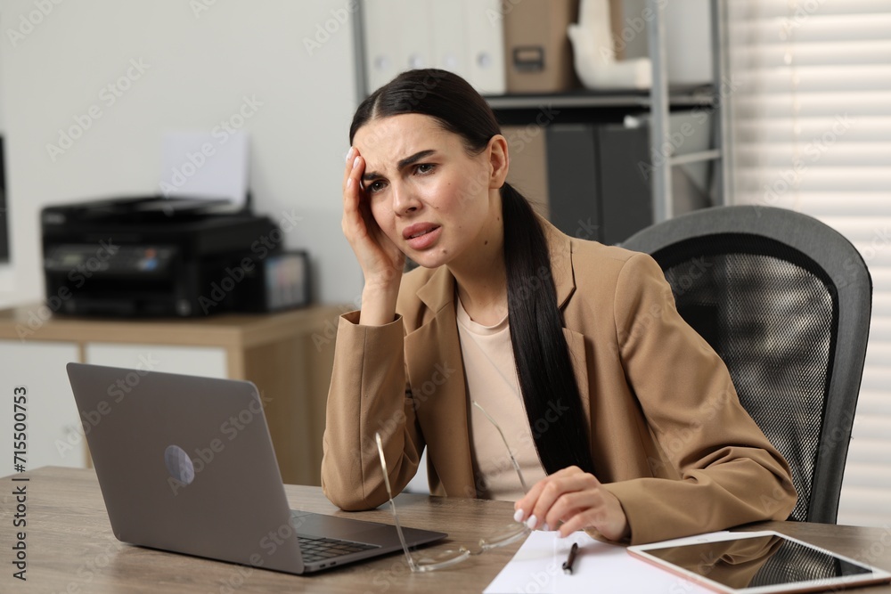 Woman suffering from headache at workplace in office Woman suffering from headache at workplace in office